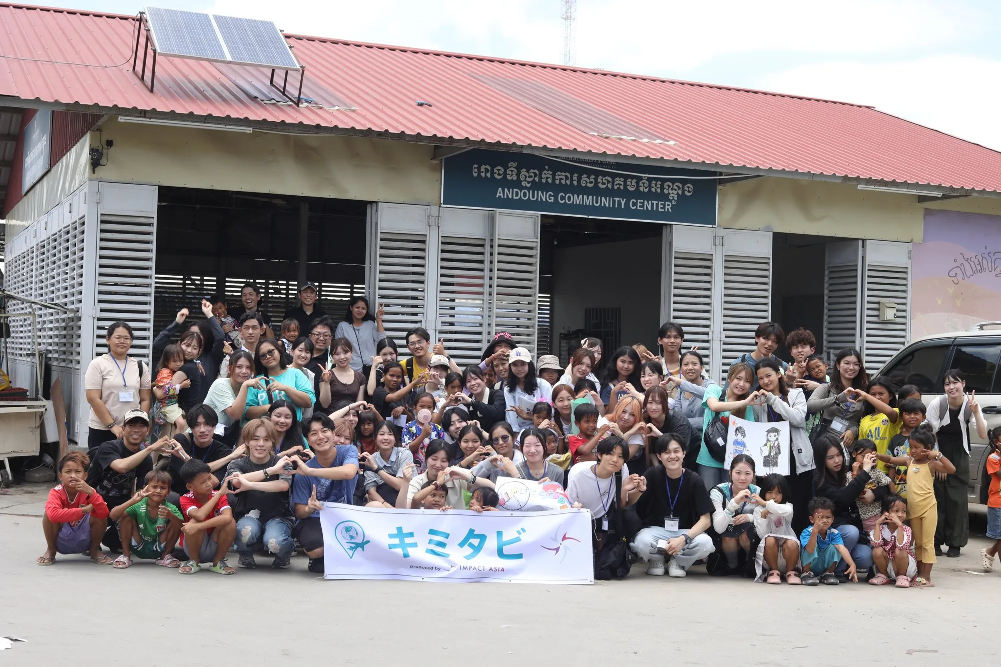 キミタビの横断幕を持つ参加者と現地の子どもたちの集合写真